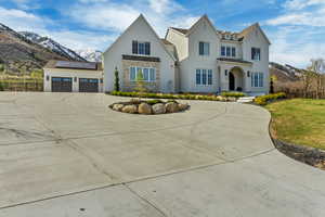 View of front of house featuring a mountain view, stone siding, fence, curved driveway, and roof mounted solar panels