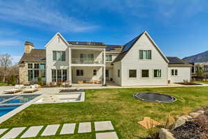 Back of house with outdoor lounge area, roof mounted solar panels, a patio, and a balcony