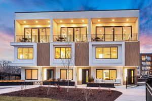 Back of house at dusk featuring a patio area, a balcony, an outdoor hangout area, and stucco siding