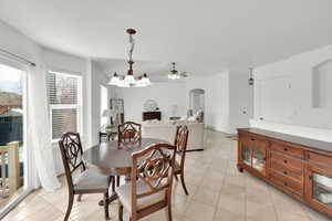Dining area featuring light tile patterned floors, a ceiling fan, and arched walkways