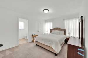 Bedroom with light colored carpet, baseboards, and ensuite bath