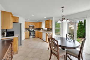 Kitchen with a chandelier, light countertops, backsplash, under cabinet range hood, and appliances with stainless steel finishes