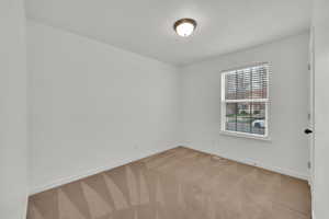 Empty room featuring visible vents, baseboards, and light carpet