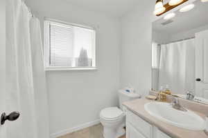 Bathroom featuring vanity, tile patterned flooring, visible vents, toilet, and baseboards