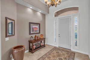 Foyer entrance featuring light tile patterned floors, a notable chandelier, and baseboards