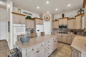 Kitchen featuring backsplash, a kitchen island, visible vents, appliances with stainless steel finishes, and a sink