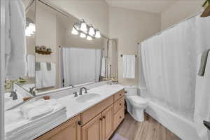 Bathroom with shower / bath combo, toilet, vanity, and wood finished floors