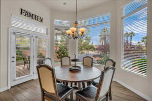 Dining space with wood finished floors, an inviting chandelier, baseboards, and visible vents