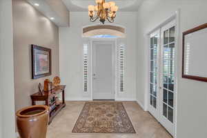 Foyer entrance featuring french doors, baseboards, a notable chandelier, and light tile patterned flooring
