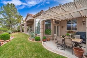 Exterior space with a pergola, a patio area, stucco siding, and a lawn