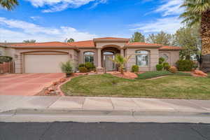 Mediterranean / spanish-style home featuring stucco siding, a front yard, a tile roof, a garage, and driveway