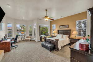 Bedroom with a textured ceiling, baseboards, a ceiling fan, and carpet