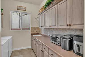 Laundry room featuring separate washer and dryer, a sink, cabinet space, a toaster, and light tile patterned flooring