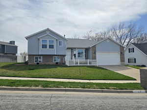 View of front of home with a garage, a front yard, fence, brick siding, and concrete driveway