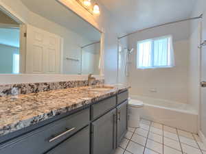 Bathroom featuring vanity, toilet, tile patterned flooring, and shower / bathtub combination