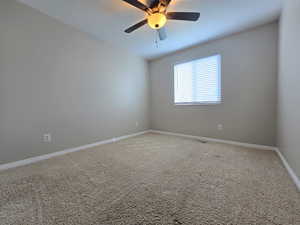 Carpeted empty room with visible vents, baseboards, and a ceiling fan