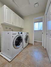 Clothes washing area with light tile patterned floors, visible vents, washer and dryer, baseboards, and cabinet space