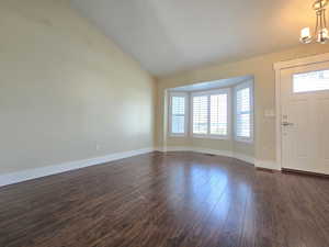 Entrance foyer featuring a chandelier, plenty of natural light, and dark wood-style floors