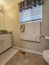 Bathroom featuring toilet, vanity, baseboards, and visible vents