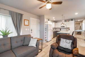 Living room featuring light wood-style flooring, a ceiling fan, and recessed lighting
