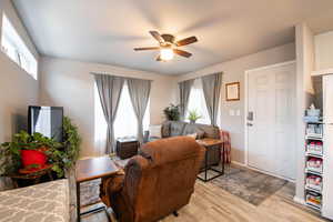 Living area featuring a wealth of natural light, light wood-style flooring, baseboards, and ceiling fan