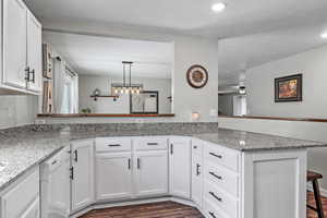 Kitchen featuring a peninsula, dishwasher, white cabinetry, and dark wood-style flooring