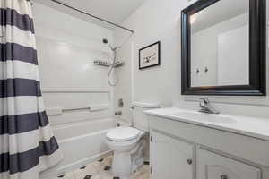 Full bath featuring tile patterned floors, vanity, shower / tub combo with curtain, and toilet