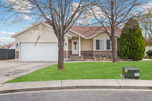 Single story home featuring a garage, a front yard, fence, brick siding, and concrete driveway