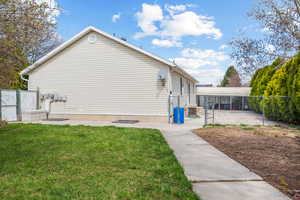 View of home's exterior featuring central AC unit, a gate, fence, and a lawn