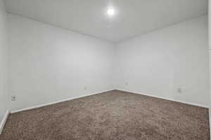 Carpeted spare room featuring baseboards
