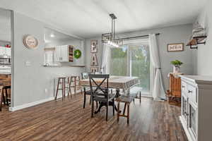 Dining area featuring baseboards, a textured ceiling, and dark wood-style floors