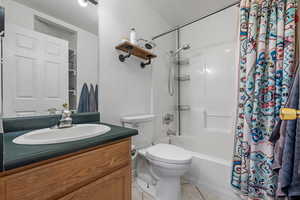 Bathroom with tile patterned floors, shower / tub combo, vanity, and toilet