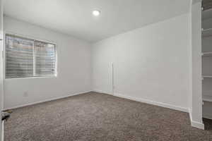 Carpeted spare room with baseboards and a textured wall