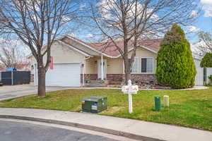 Ranch-style house with an attached garage, fence, concrete driveway, brick siding, and a front lawn