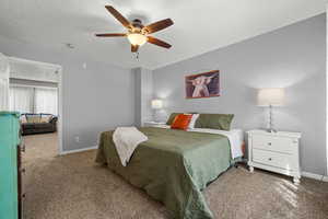Carpeted bedroom featuring baseboards and ceiling fan