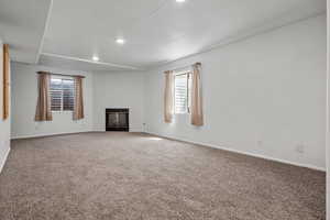 Unfurnished living room with recessed lighting, baseboards, a glass covered fireplace, and carpet floors