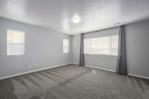 Empty room with visible vents, a textured ceiling, baseboards, and carpet floors