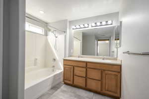 Full bath with double vanity, a sink, tile patterned flooring, and shower / bathtub combination