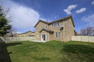 Back of property with a patio, stucco siding, a fenced backyard, a tile roof, and a lawn