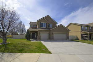 View of front of house featuring concrete driveway, a front yard, a tiled roof, and fence