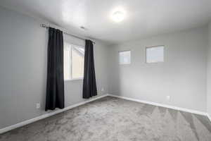 Carpeted spare room with visible vents and baseboards