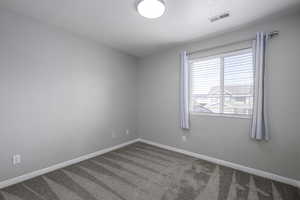 Spare room with visible vents, baseboards, and carpet floors