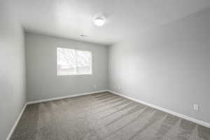 Carpeted spare room featuring baseboards and visible vents