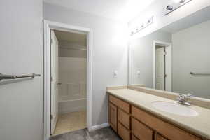 Bathroom featuring vanity, baseboards, and shower / bathing tub combination