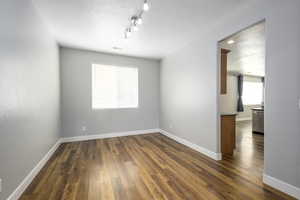 Empty room featuring dark wood-style flooring, a textured ceiling, and baseboards