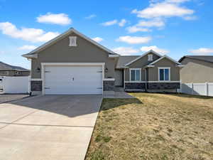 View of front of house featuring a garage, stucco siding, a front yard, fence, and concrete driveway