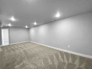 Finished basement featuring a textured ceiling, visible vents, recessed lighting, carpet flooring, and baseboards