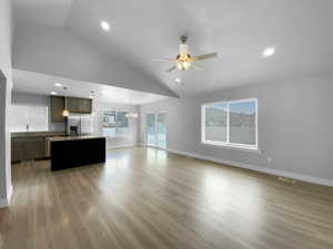 Living room with light wood-style flooring, ceiling fan with notable chandelier, and baseboards