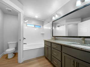 Bathroom with visible vents, a sink, toilet, double vanity, and wood finished floors