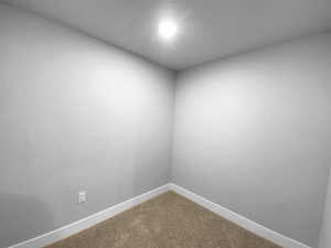 Unfurnished room with baseboards and dark colored carpet